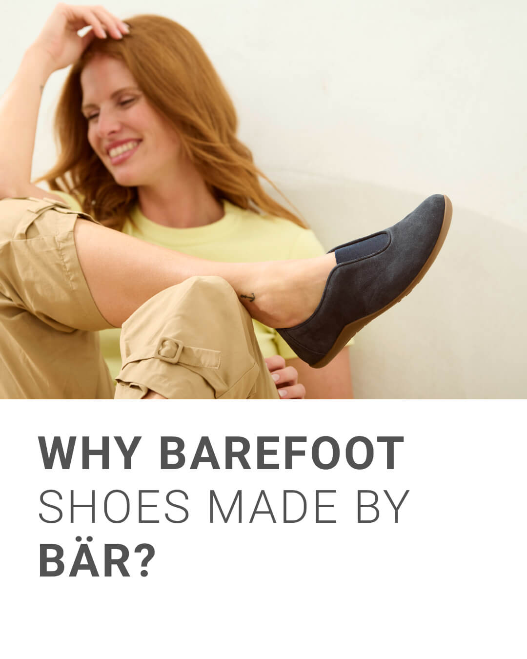 Smiling woman wearing comfortable BÄR barefoot shoes while sitting casually indoors.