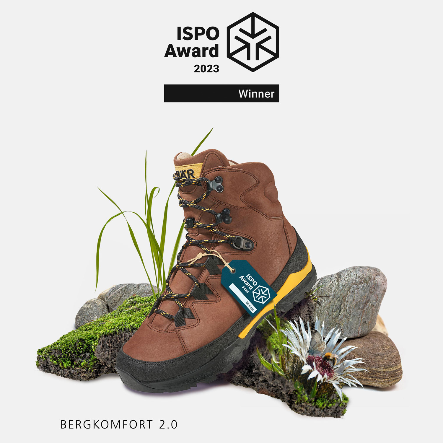 Bergkomfort 2.0 hiking boot with ISPO Award 2023 badge, surrounded by rocks and moss.