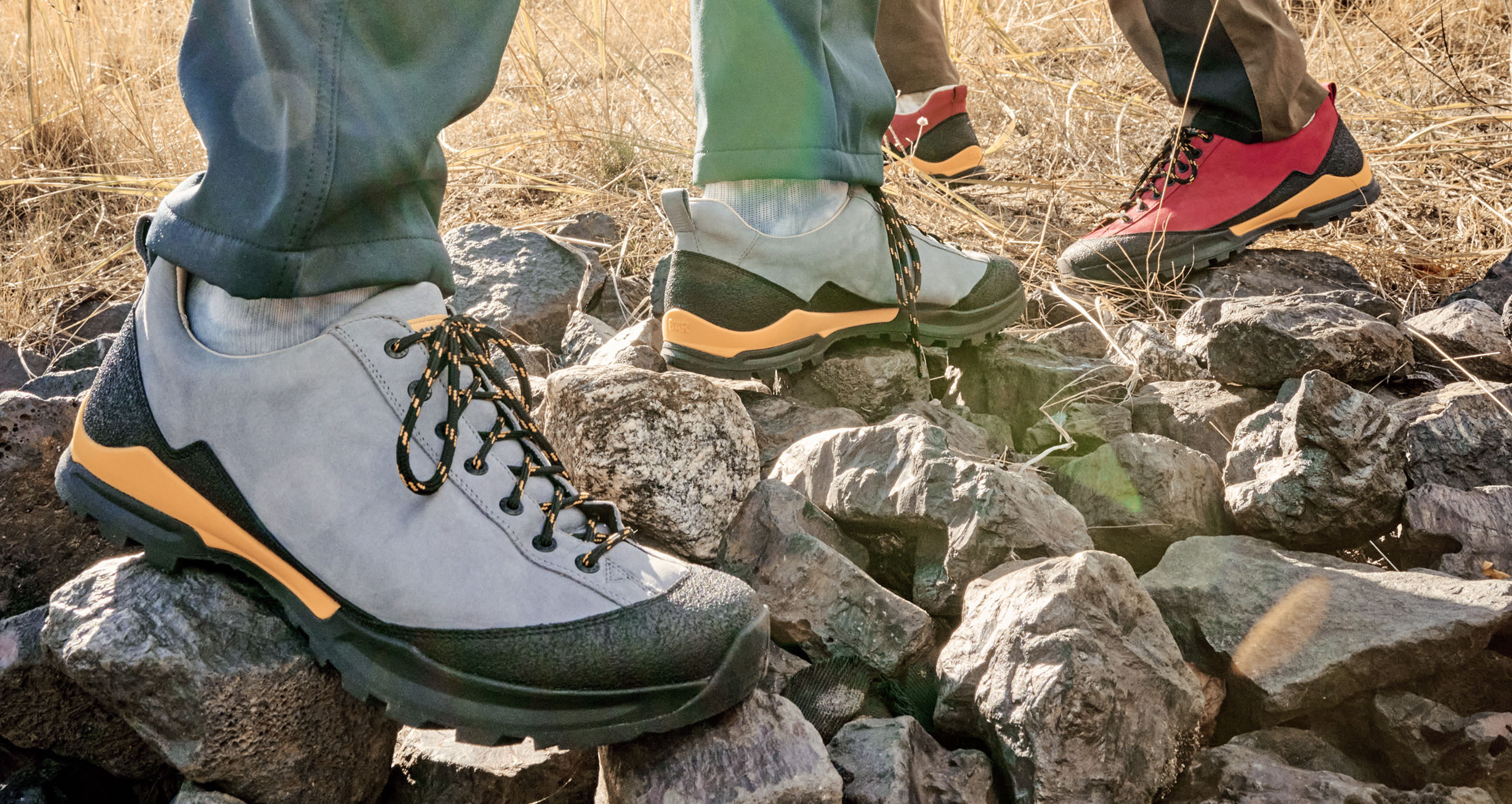 Two pairs of hiking shoes on rocky ground in a natural setting