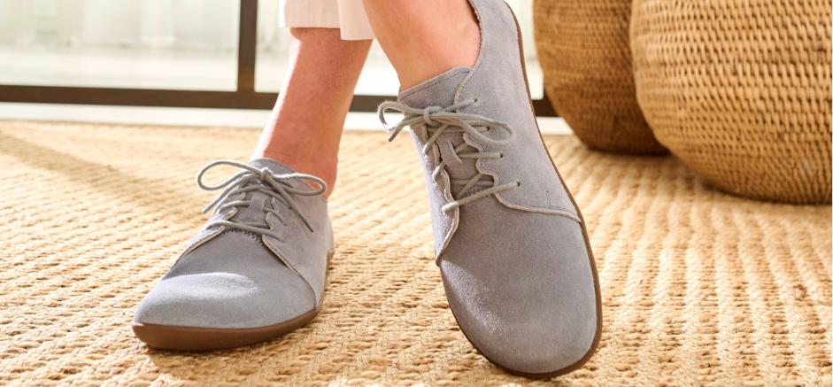 Person wearing comfortable gray suede casual shoes on a woven rug