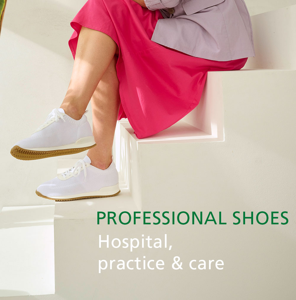 Person wearing comfortable white shoes and a pink skirt suitable for hospital and care environments