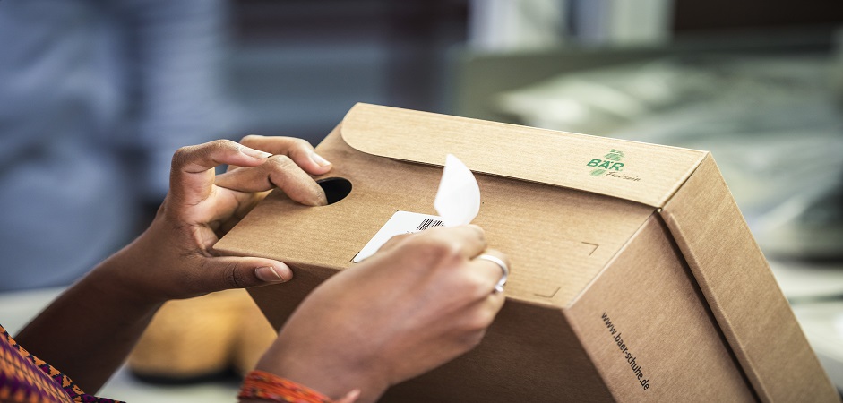 Close-up of hands peeling a label from a cardboard box at a counter