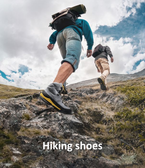 Two hikers wearing sturdy hiking shoes, walking up a rocky path in the mountains