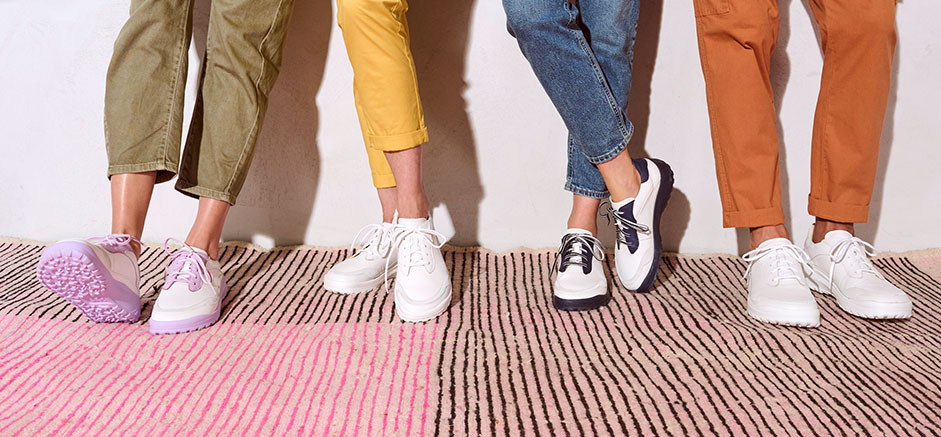 Close-up of legs in fashionable sneakers and vibrant pants on a textured striped rug