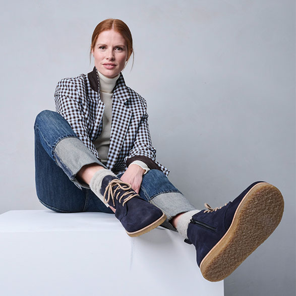 Woman wearing checkered jacket, jeans, and blue ankle boots