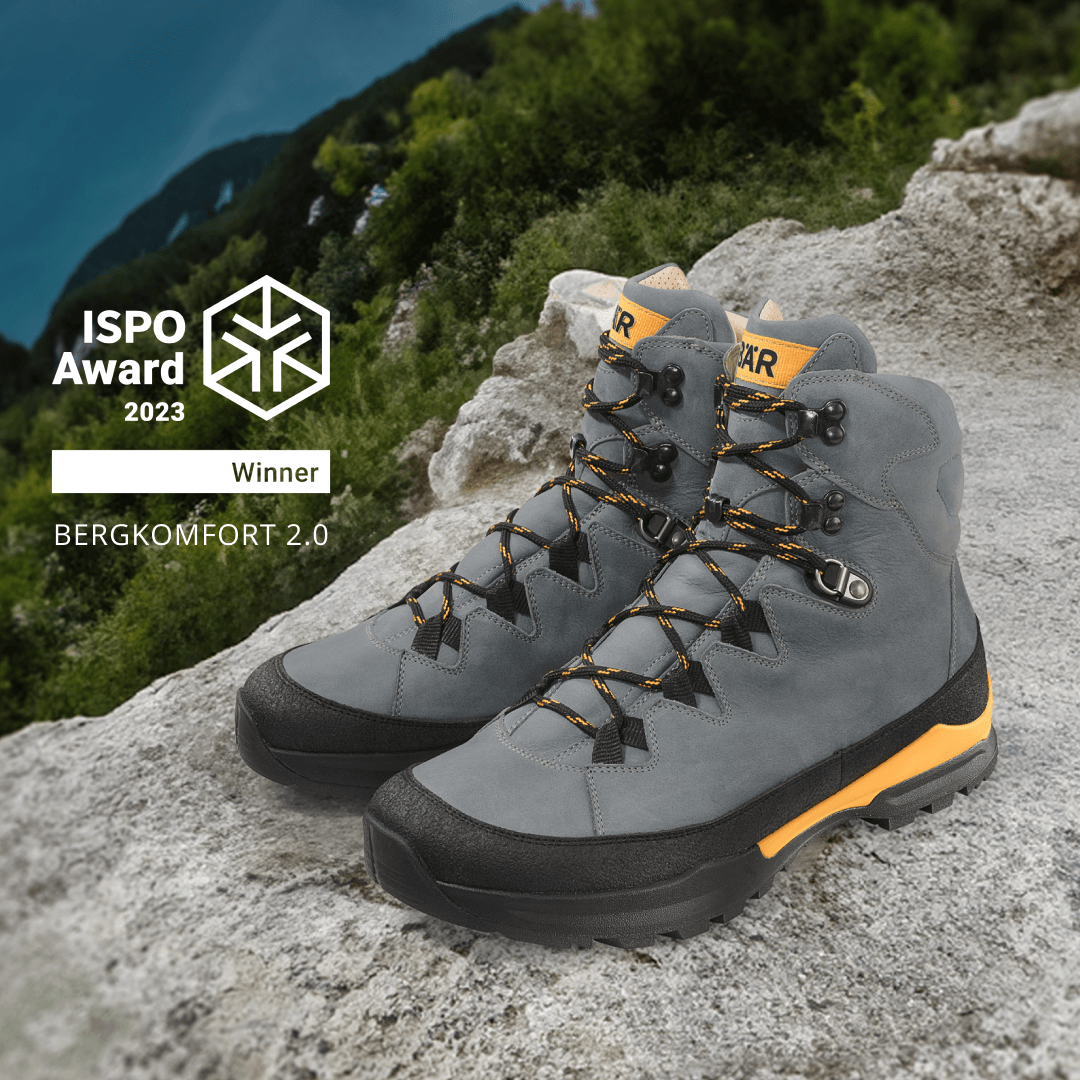 Gray and yellow Bergkomfort 2.0 hiking boots on rocky terrain, winner of ISPO Award 2023