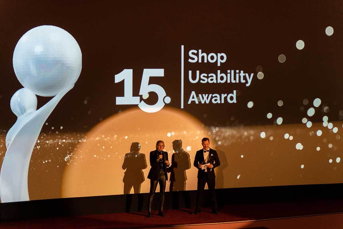 Presenters at the 15th Shop Usability Award ceremony with a vibrant stage setup.