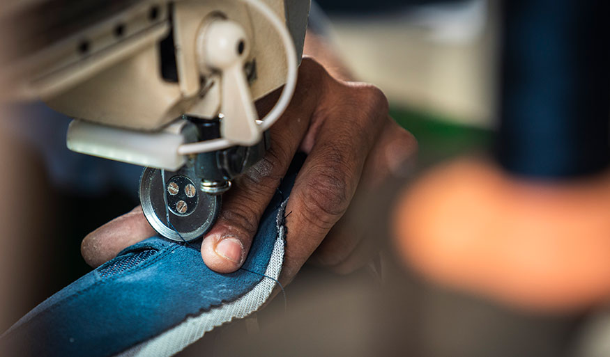 Hand using a sewing machine to stitch blue fabric
