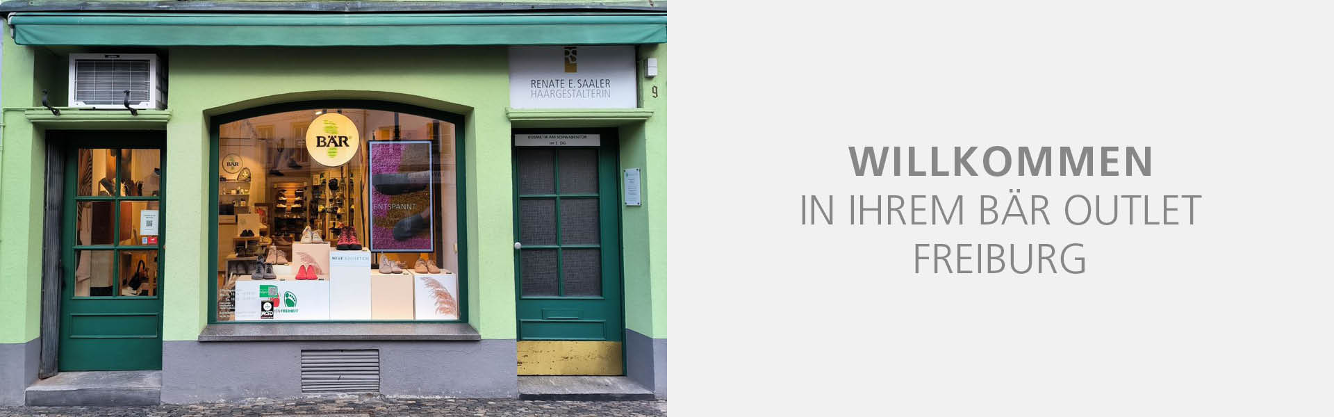 Street view of the BÄR outlet store in Freiburg with green facade and shoe display in the window.