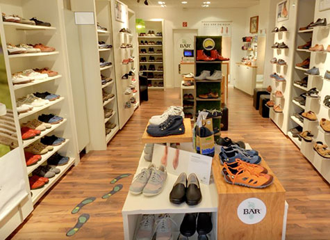 A well-organized shoe store showcasing sneakers, sandals, and formal shoes on wooden shelves