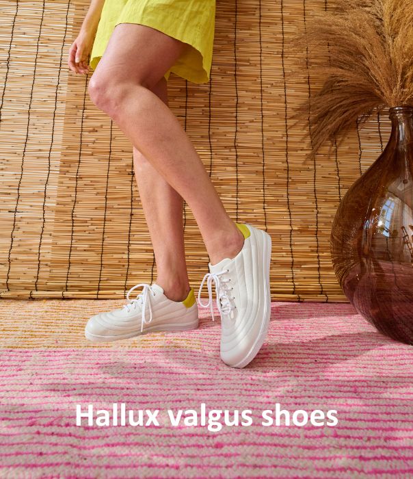 Woman wearing comfortable hallux valgus white sneakers indoors on colorful rug